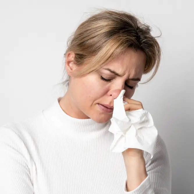 Pharmacy First Sinusitis - Woman holding tissue to her nose